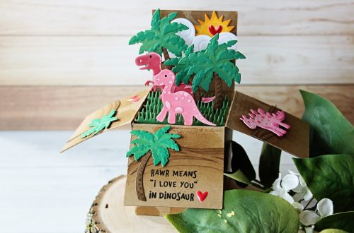 Die D-Lites Inspiration | Dinosaur Pop Up Card. Video tutorial by Nichol Spohr for Spellbinders using S2-273 Sun and Clouds, S3-317 Dinosaurs, S3-320 Picket Fence, S3-249 Palm Trees, S4-788 Classic A2 Waves Borders, S5-233 Heart & Home Scalloped Pop Up Box #spellbinders #popupbox #diecutting handmadecard #popupcard